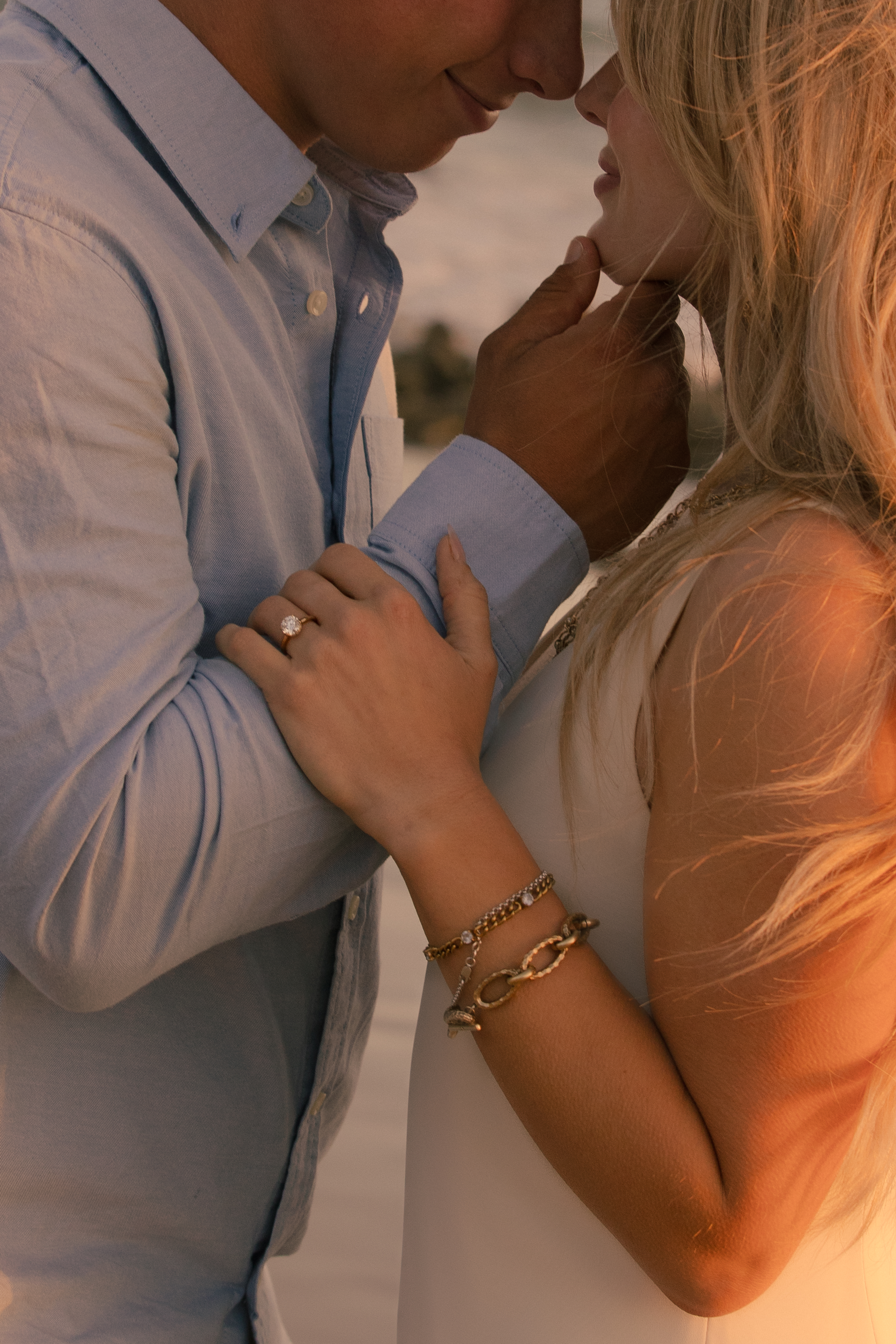 Intimate close-up of a groom touching his bride's chin, engagement ring visible on her hand